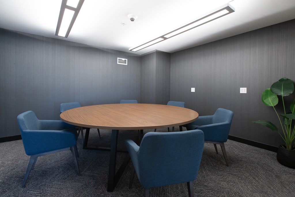 a small meeting room with a round table and blue chairs