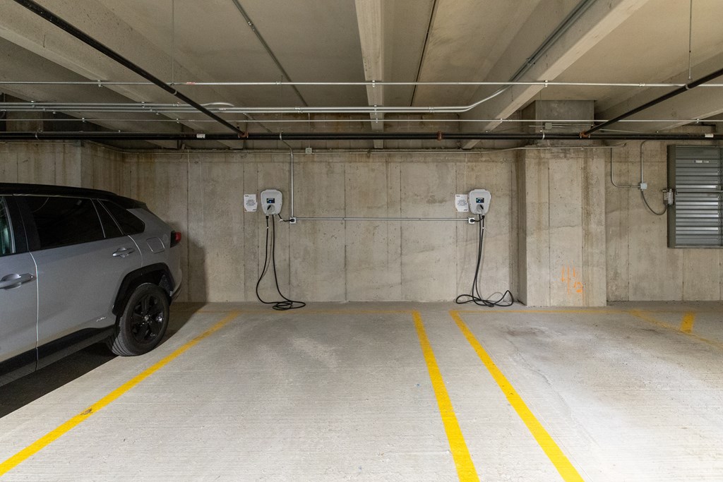 a car parked in a parking garage with two electric chargers plugged into the wall