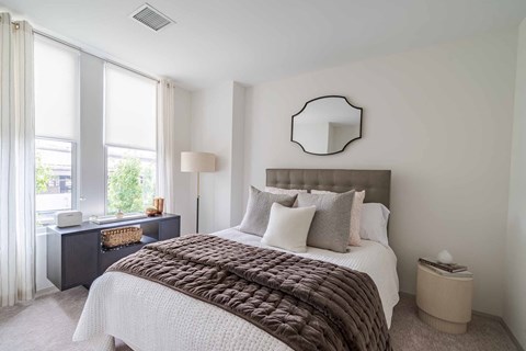 A bedroom with a large bed and a window with curtains.