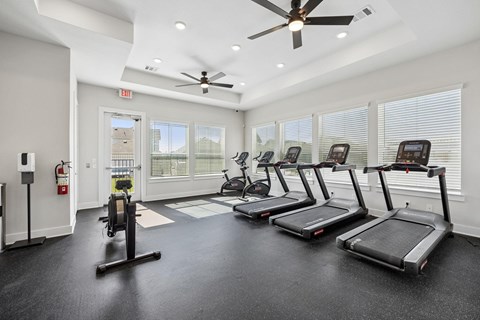 A gym with treadmills, elliptical machines, and a fire extinguisher.
