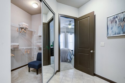 A bathroom with a blue chair and a mirror.