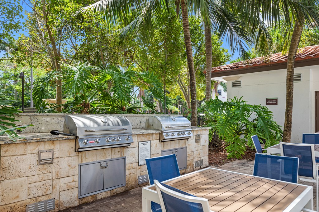 an outdoor kitchen with a table and chairs and palm trees