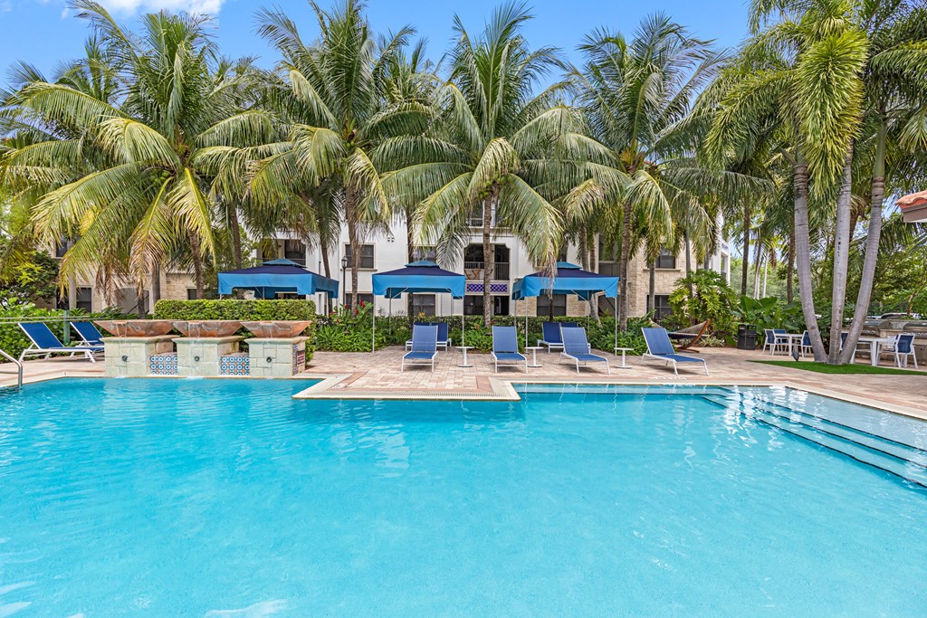 a large swimming pool with chairs and palm trees