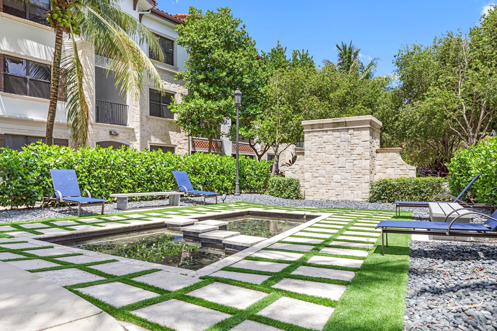 a courtyard with a fountain and two blue lounge chairs