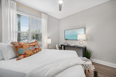 A bedroom with a large bed and a small table with a lamp.