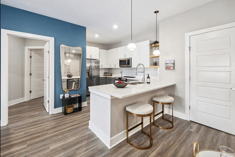 A kitchen with a white counter and bar stools.