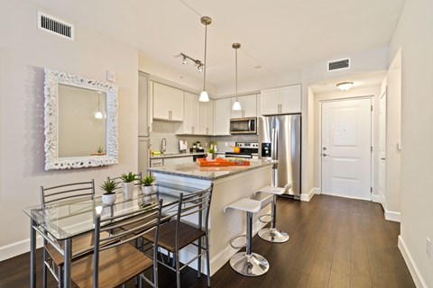 A kitchen with a glass table and bar stools.