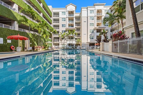 A swimming pool in front of a building with a white fence.