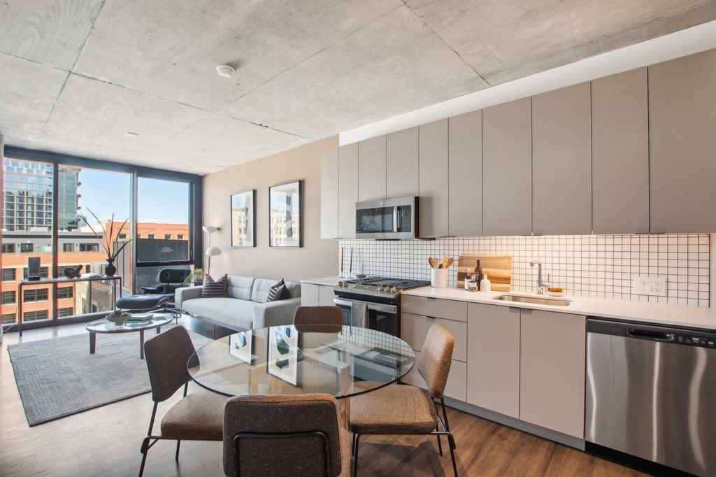 a living room with a kitchen and a glass table at Arthur on Aberdeen apartments in the Fulton Market District of Chicago, IL