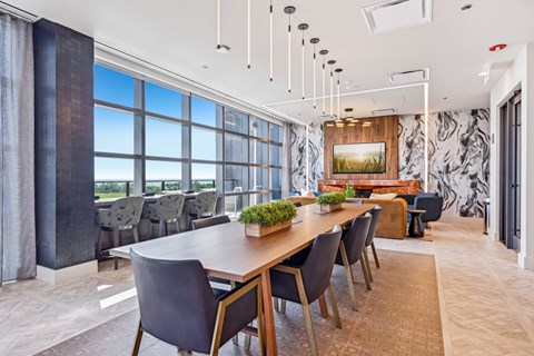 a dining room with a long table and chairs and a wall of windows