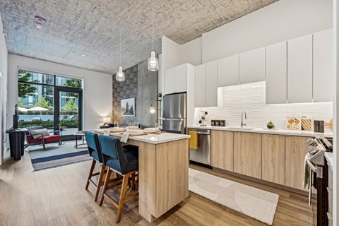 a kitchen with white cabinets and a bar and a living room