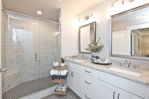 A bathroom with a walk-in shower, double sinks, and a large mirror.