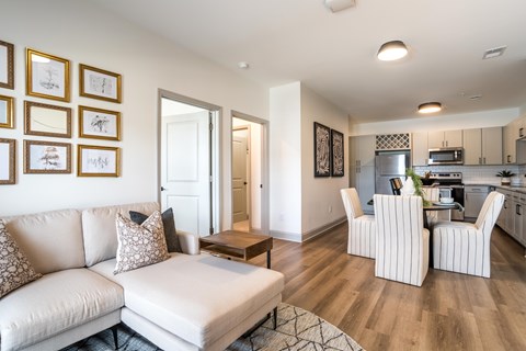 A living room with a white couch and a kitchen in the background.