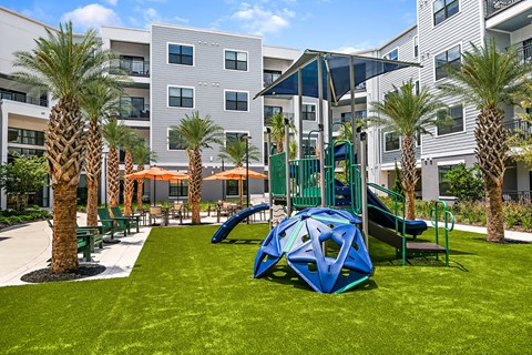 A playground with a blue slide and a green bench.