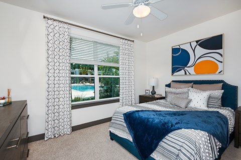 A bedroom with a bed, nightstand, and a painting on the wall.