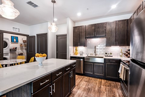 A modern kitchen with dark wood cabinets and stainless steel appliances.