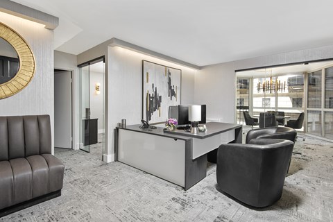 A modern office space with a black leather chair and a grey reception desk.