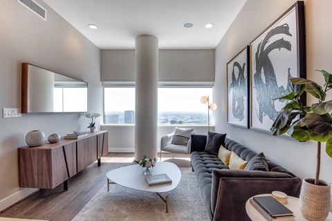 A living room with a brown couch, a white coffee table, and a large painting on the wall.