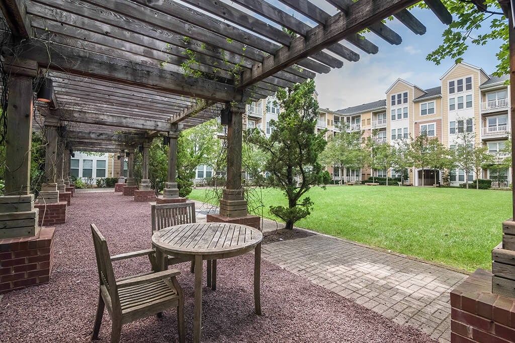 a pergola with a table and chairs in a courtyard