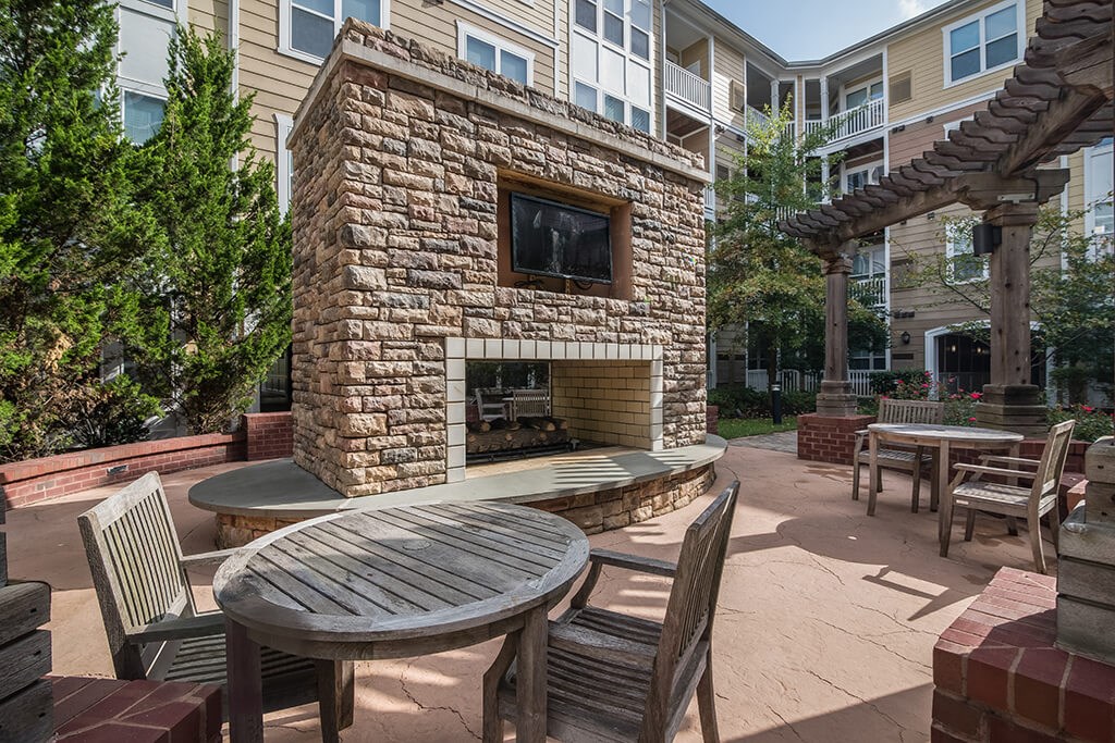 a patio with a stone fireplace and tables and chairs