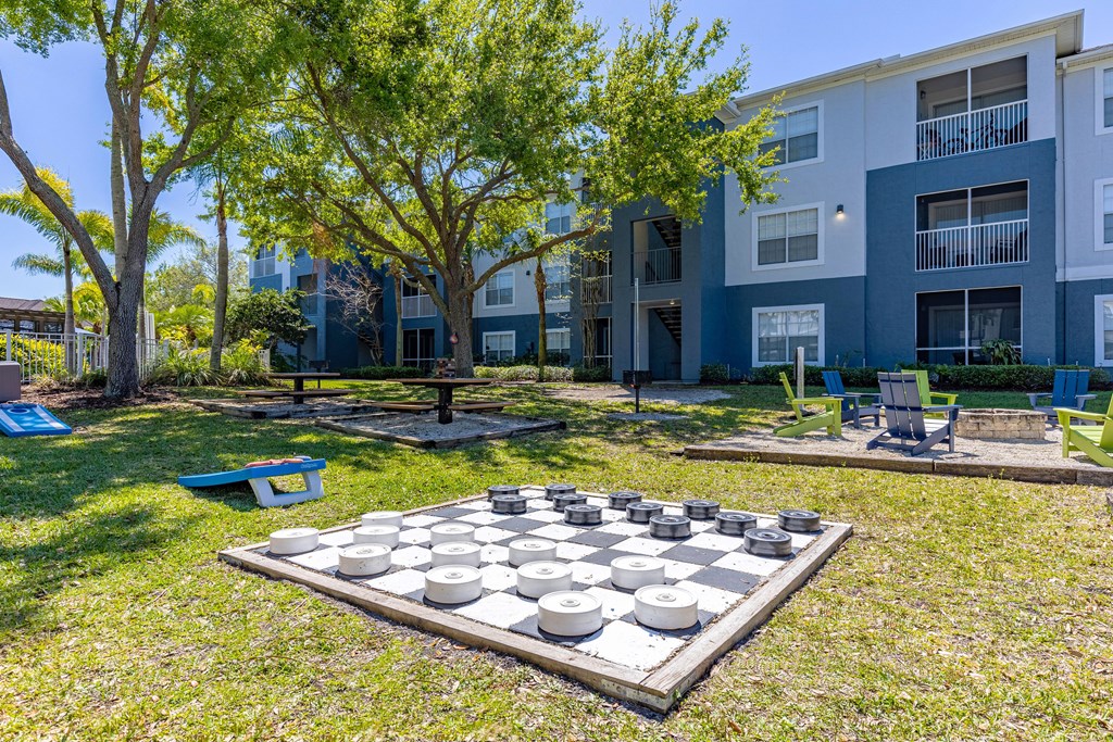 a large chess board in the middle of a grassy area with an apartment building in the