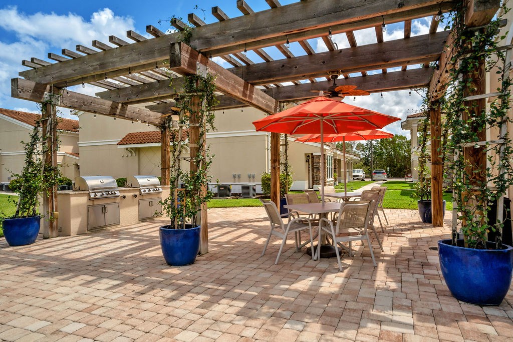 a patio with a pergola and tables with umbrellas