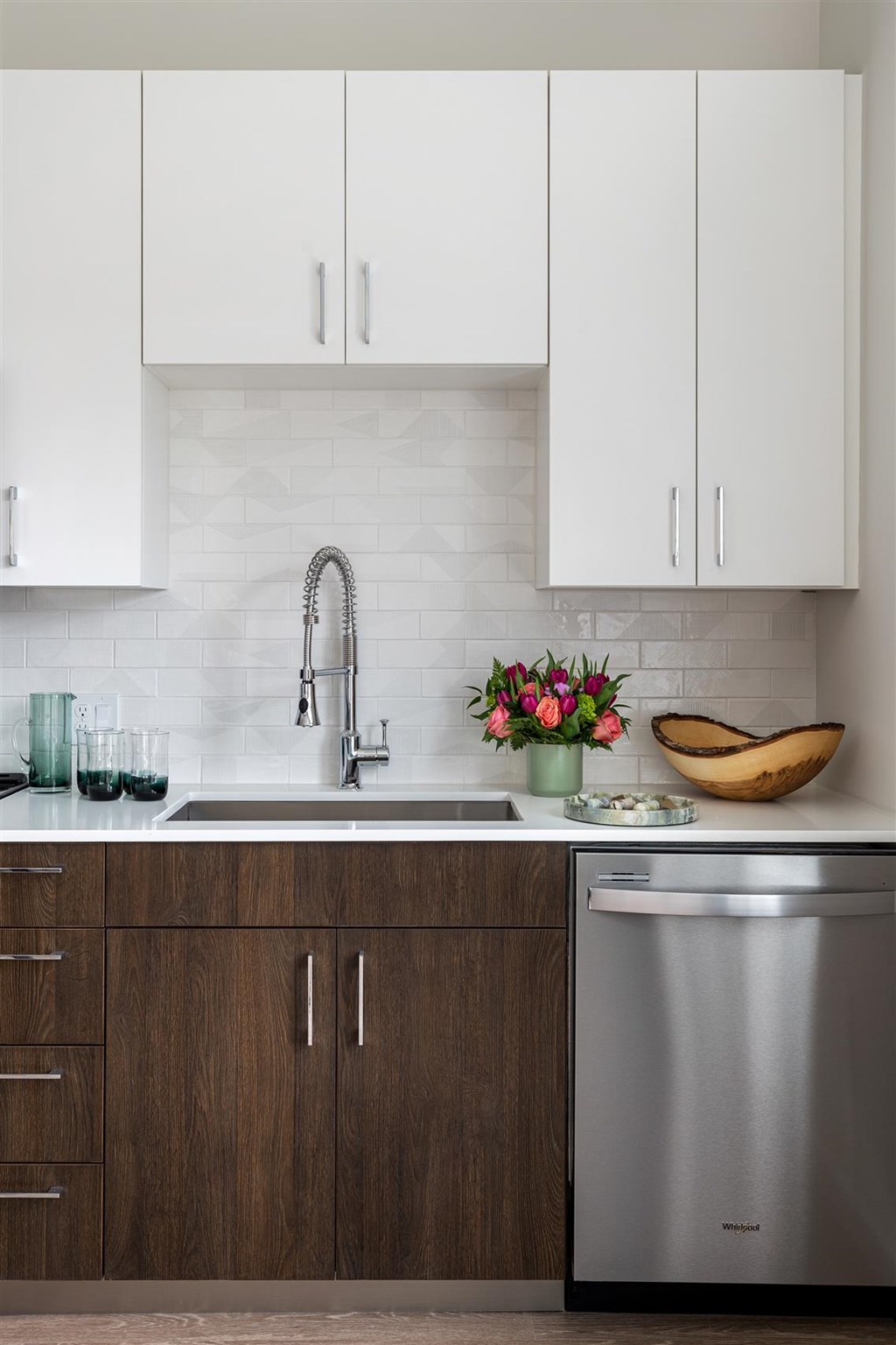 a kitchen with white cabinets and a stainless steel dishwasher