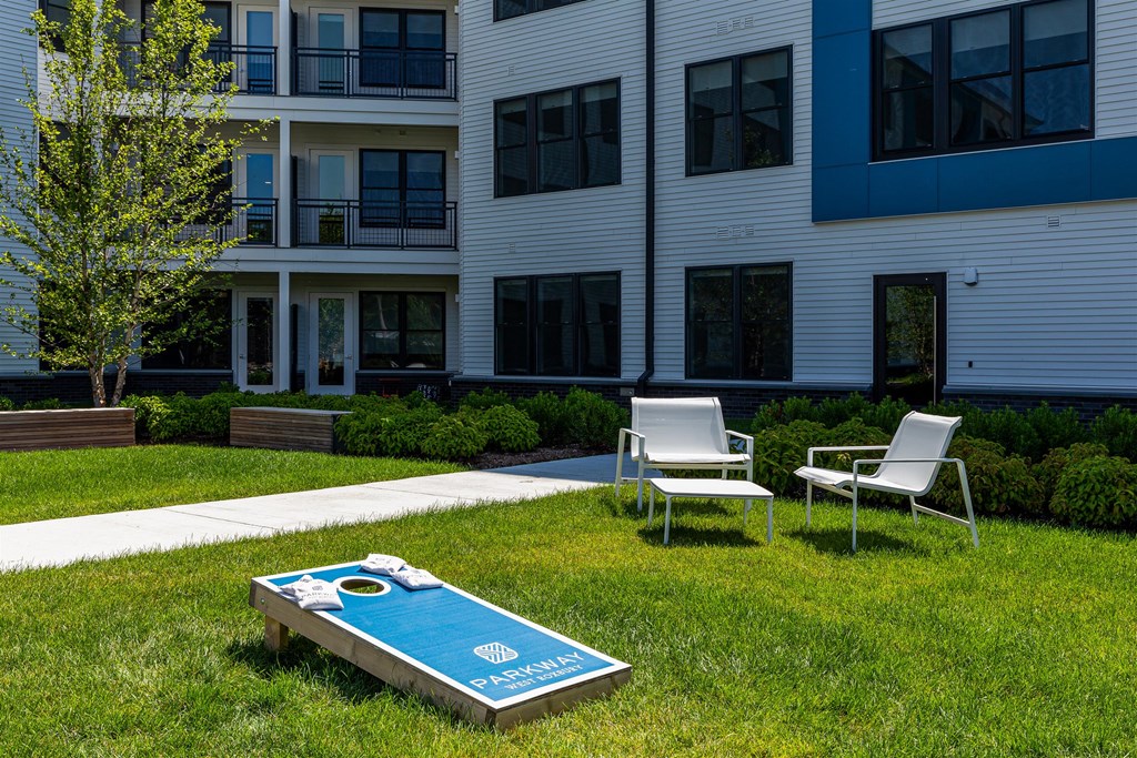 a yard with a pool and two chairs in front of an apartment building