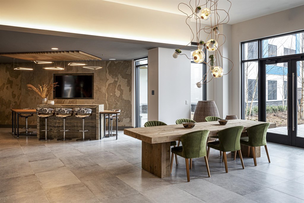 a dining room with a long wooden table and chairs and a tv on the wall