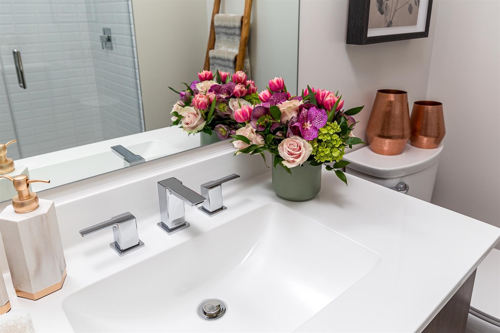 a white bathroom with a vase of flowers on the sink