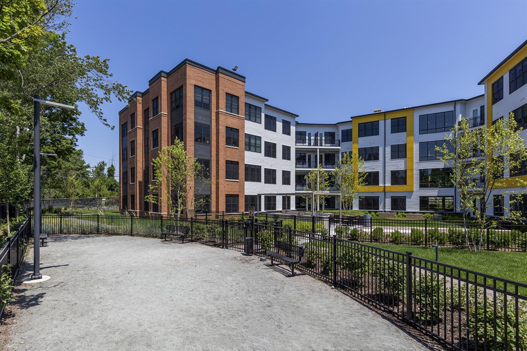 a courtyard with benches and a fence in front of a building