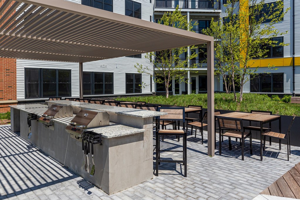 a barbecue grill on a patio with tables and chairs