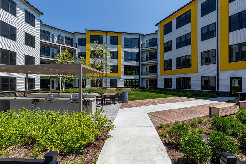 an exterior view of an apartment complex with a walkway and benches