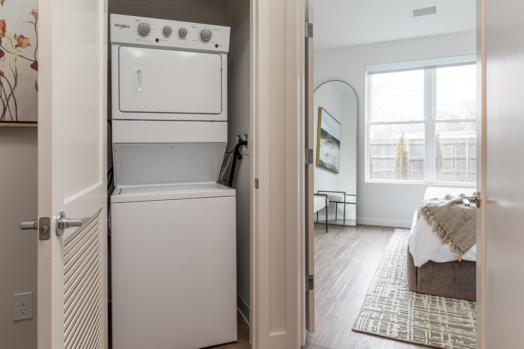 a white washer and dryer in a room next to a bedroom