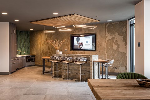 A modern kitchen with a wooden table and bar stools.