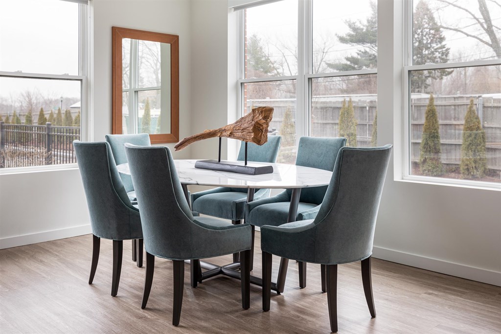 a dining room with a table and chairs and large windows