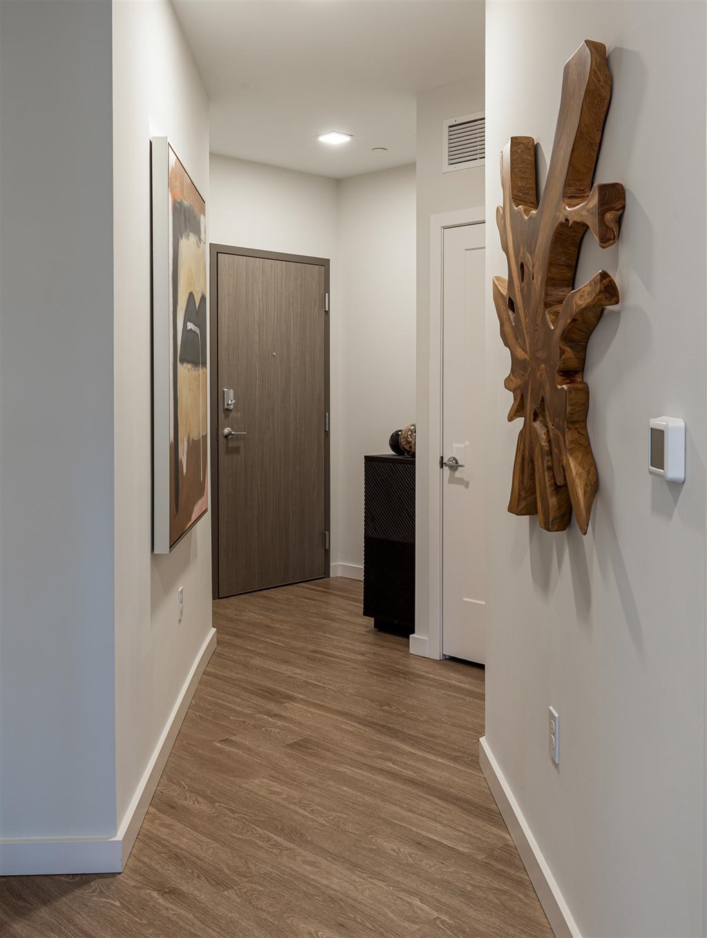 a hallway with a driftwood sculpture on the wall and a door to a room