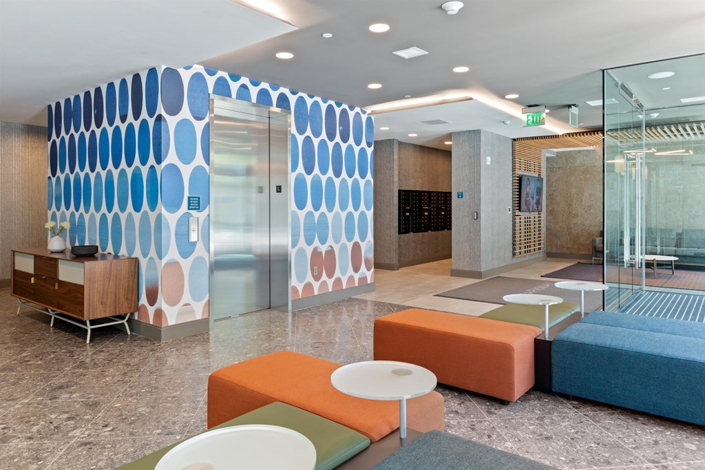 a lobby with orange and blue furniture and a large wall with a blue and white