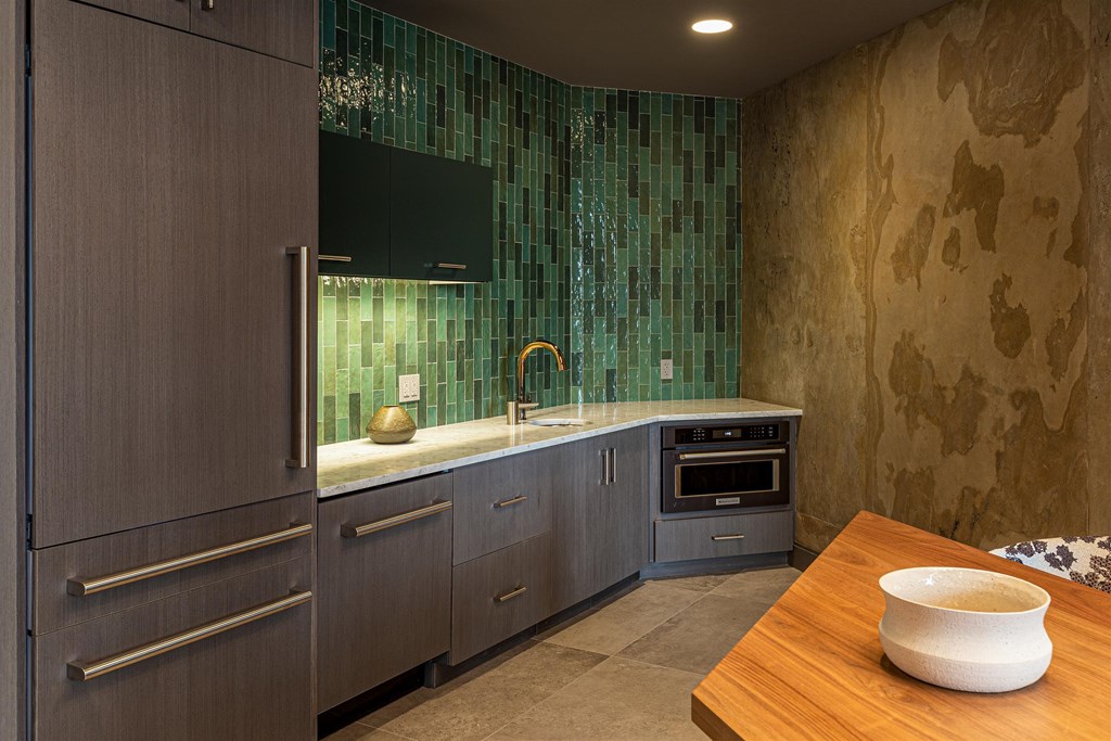 a kitchen with green tiles and a wooden table