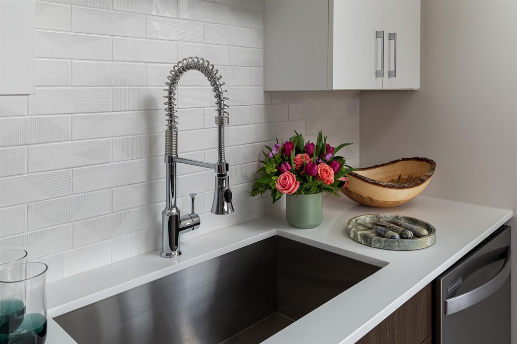 a kitchen counter with a sink and a vase of flowers