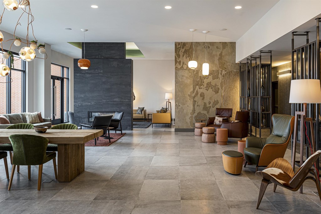 the lobby of a hotel with chairs and tables and a living room with large windows