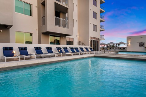 a swimming pool with blue chairs next to a building