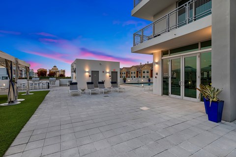 a patio with chairs and a building with glass doors