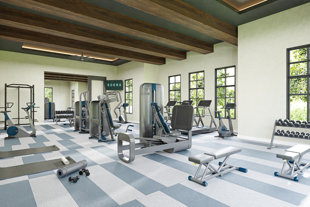 a gym with cardio equipment and weights in a building with windows