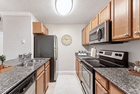 A kitchen with a black refrigerator and stove, wooden cabinets, and a clock on the wall.