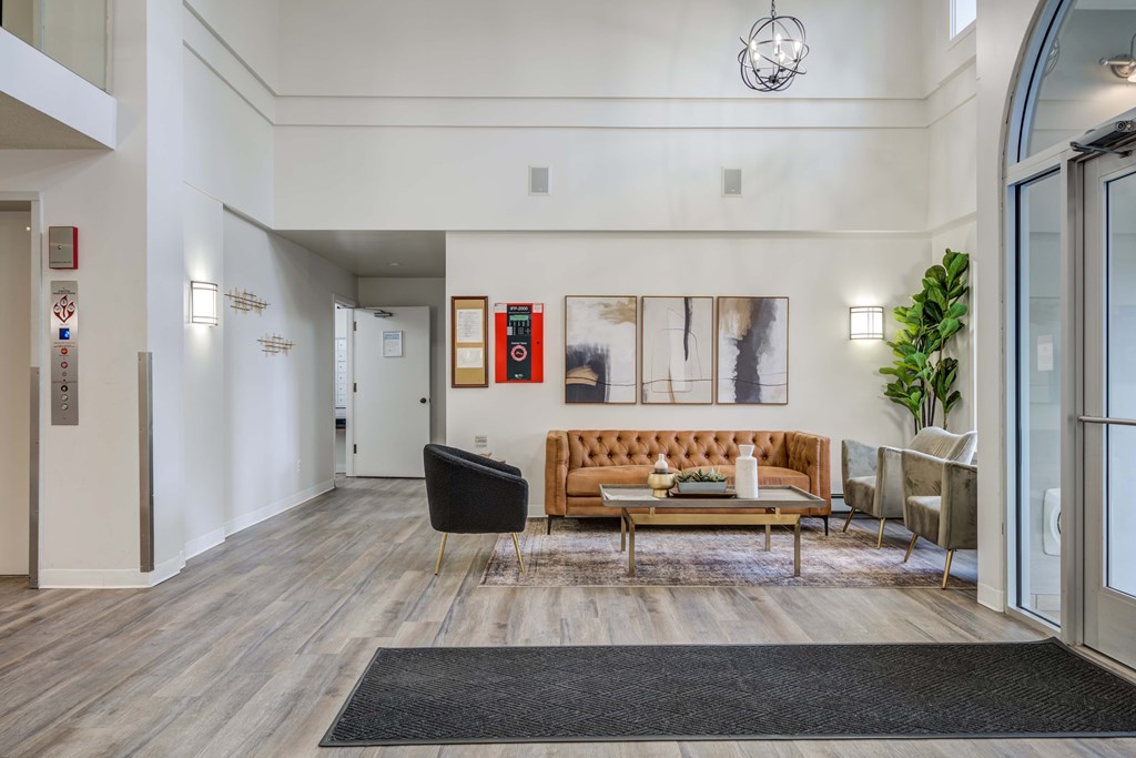 A living room with a brown couch and a black chair.