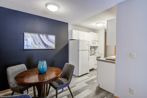 a dining room with a table and chairs and a kitchen with a refrigerator