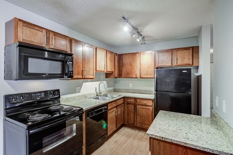 an empty kitchen with wooden cabinets and black appliances