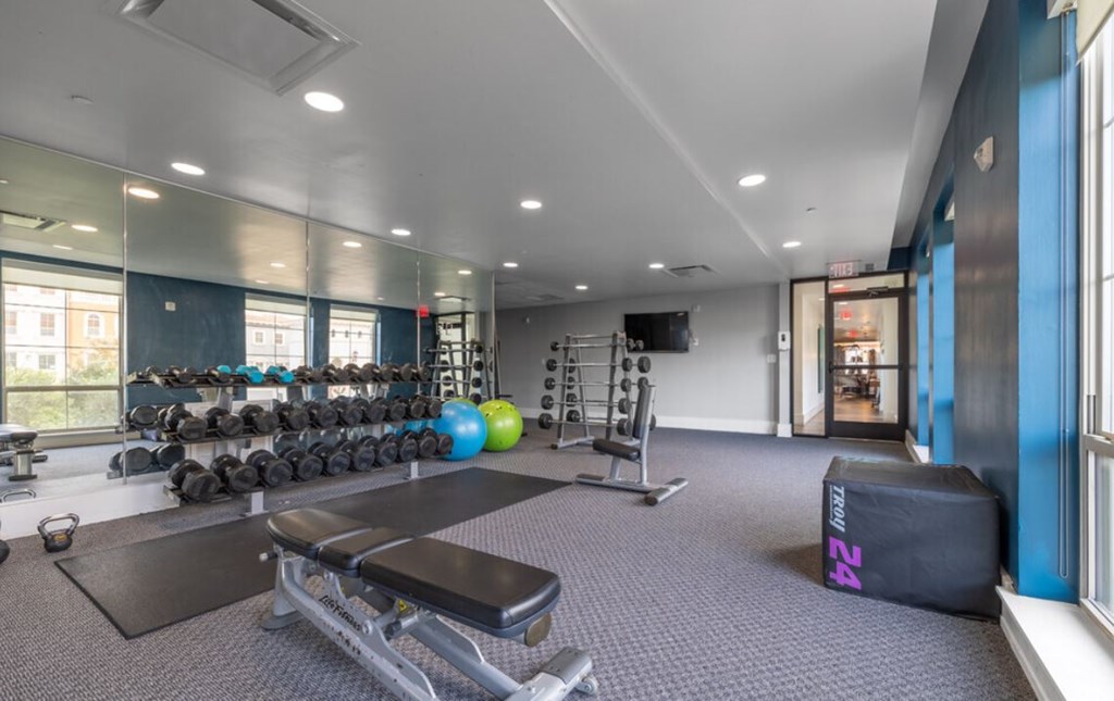 a gym with weights and dumbbells on the floor and a window