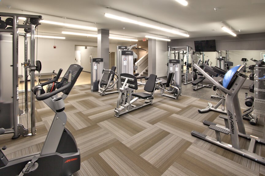 a gym with various cardio machines and weights on a wooden floor